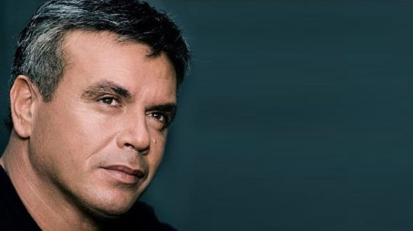 Πορτρέτο του τραγουδιστή Μανώλη Λιδάκη, ο οποίος "έφυγε" από τη ζωή, με φόντο σκούρο μπλε.