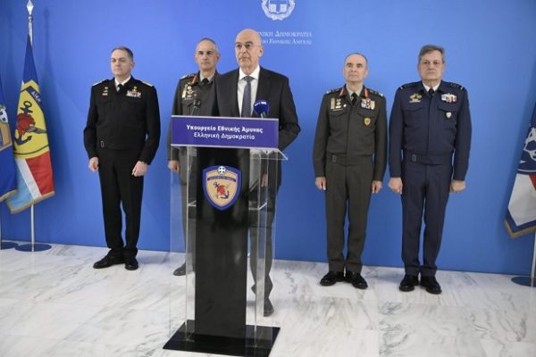 Ο Ν. Δένδιας στέκεται μπροστά σε βάθρο ομιλίας, πλαισιωμένος από στελέχη των Ενόπλων Δυνάμεων.