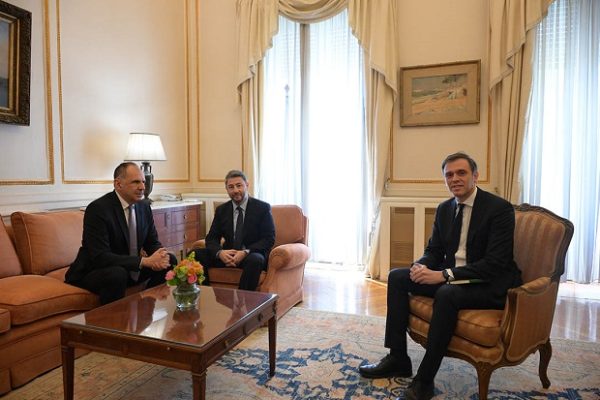 Ο Νίκος Ανδρουλάκης συνομιλεί με άλλους άνδρες σε εσωτερικό χώρο, συζητώντας για την εξωτερική πολιτική.