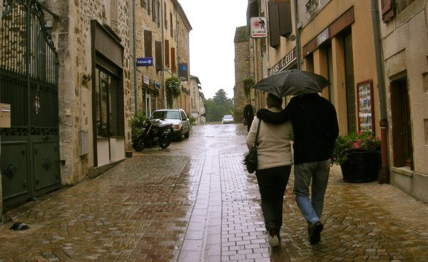 Ζευγάρι περπατάει με ομπρέλα σε βροχερό δρόμο, καθώς ο καιρός αναμένεται να βελτιωθεί.
