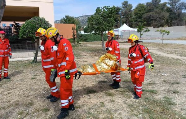 Μέλη του Ελληνικού Ερυθρού Σταυρού μεταφέρουν ασθενή σε φορείο κατά τη διάρκεια μεγάλης επιχειρησιακής άσκησης ετοιμότητας.