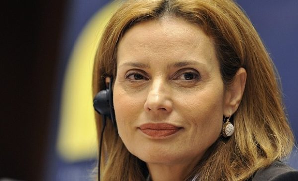 Η Κ. Μπατζελή με ακουστικά, σε εκδήλωση του ΠΑΣΟΚ, με φόντο μπλε και κίτρινες αποχρώσεις.