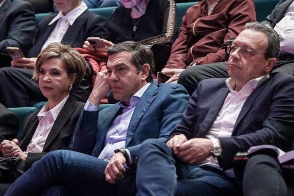 Ο Αλέξης Τσίπρας και η Όλγα Γεροβασίλη παρακολουθούν εκδήλωση, με τον Τσίπρα να δείχνει προβληματισμένος.