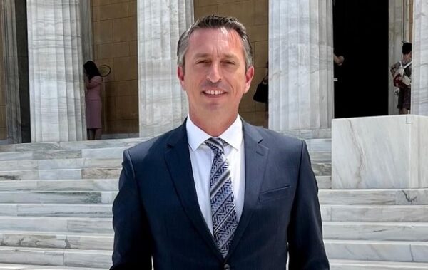 Ο Π. Μαντάς μιλάει για την Ελλάδα ως σταθερή πυξίδα σε έναν ταραγμένο γεωπολιτικό χάρτη, μπροστά από κτίριο με κολώνες.