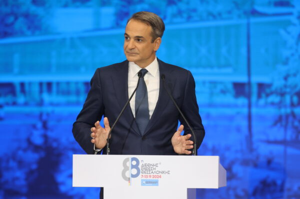 Ο Κυριάκος Μητσοτάκης μιλάει στο βήμα της Διεθνούς Έκθεσης Θεσσαλονίκης, με το βλέμμα του στραμμένο στο κοινό.