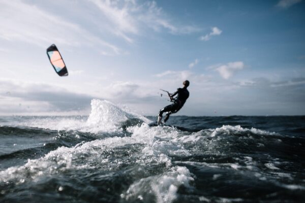 Αθλητής κάνει kitesurfing σε κύματα, προστατεύοντας τον εαυτό του από τραυματισμούς στα θαλάσσια σπορ.