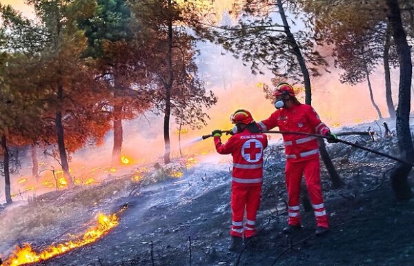 Εθελοντές Σαμαρείτες του Ελληνικού Ερυθρού Σταυρού αντιμετωπίζουν πυρκαγιά, προσφέροντας βοήθεια σε δύσκολες συνθήκες.