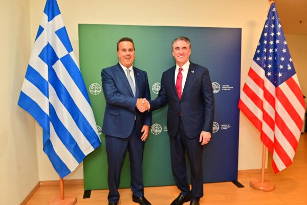 Ο Doug Burgum και ο Έλληνας ομόλογός του ανταλλάσσουν χειραψία μπροστά από τις σημαίες Ελλάδας και ΗΠΑ, τονίζοντας τις συμμαχίες.