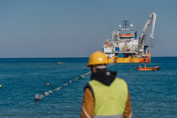 Εργάτης επιβλέπει την εγκατάσταση του καλωδίου για την ηλεκτρική διασύνδεση Ελλάδας-Κύπρου με πλοίο υποστήριξης στη θάλασσα.