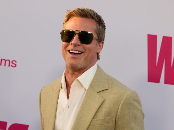 Ο Brad Pitt χαμογελάει φορώντας γυαλιά ηλίου, με φόντο την πολυτελή έπαυλη που αγόρασε στα Hollywood Hills.