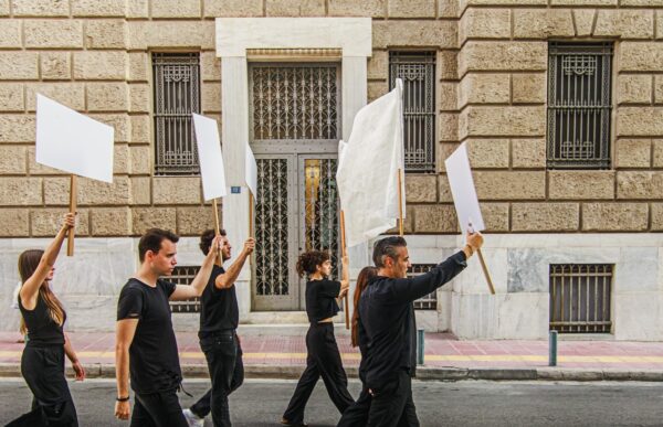 Ηθοποιοί του Θεάτρου Τέχνης Κ. Κουν κρατούν λευκές σημαίες και πλακάτ στην παράσταση «Το Δράμα της Δημοκρατίας».