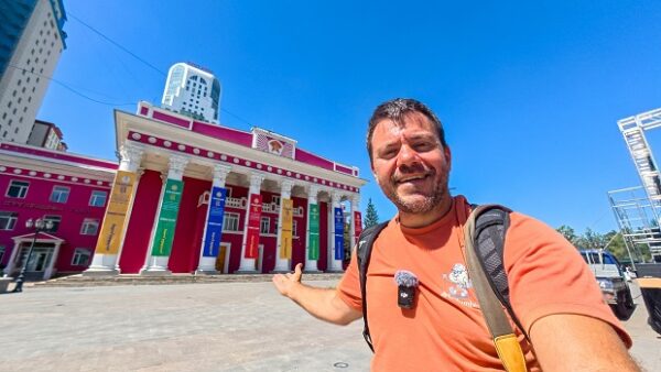Ο παρουσιαστής του Happy Traveller ποζάρει μπροστά από ένα εντυπωσιακό κτίριο στη Μογγολία, κατά τη διάρκεια του ταξιδιού του.