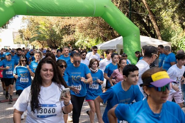 Συμμετέχοντες στο Athens Run 2025 γιορτάζουν τα 100 Χρόνια Ε.Ε.Α. κάτω από την πράσινη αψίδα εκκίνησης.