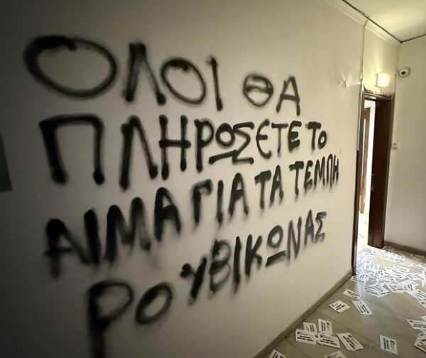 Γκράφιτι του Ρουβίκωνα στο πολιτικό γραφείο του Στράτου Σιμόπουλου, με συνθήματα στον τοίχο και χαρτιά στο πάτωμα.