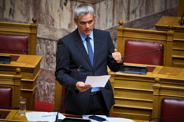 Ο Κώστας Καραγκούνης μιλάει στη Βουλή για τη μείωση των εργατικών ατυχημάτων, κρατώντας χαρτιά.