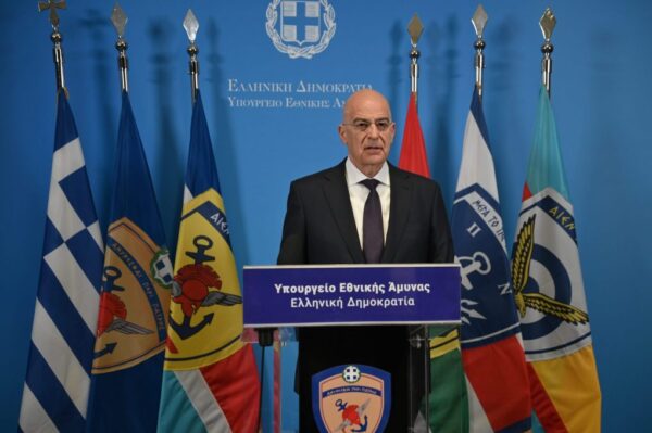 Ο Υπουργός Εθνικής Άμυνας Νίκος Δένδιας μιλάει για την Εθνική Επέτειο της 25ης Μαρτίου 1821 μπροστά από σημαίες.