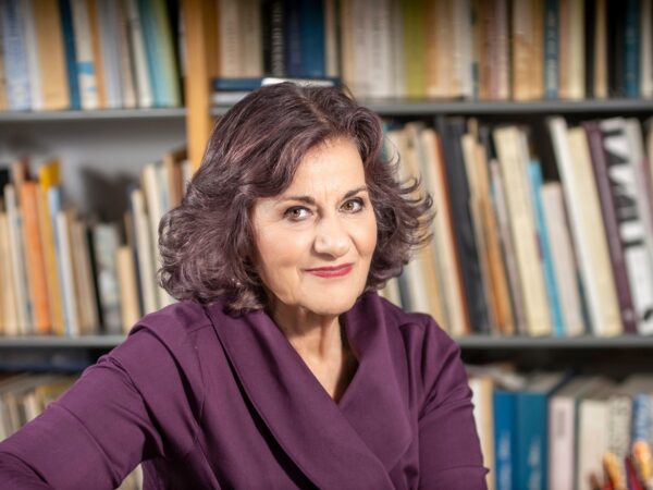 Η Θεανώ Φωτίου μπροστά από ράφια με βιβλία, εκφράζοντας τη θέση της για τα Κέντρα Πρόληψης.