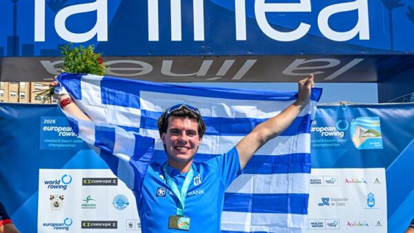 Νικητής με την ελληνική σημαία και μετάλλιο γιορτάζει την κορυφή του σε αγώνα κωπηλασίας.