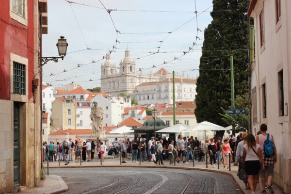 Πλήθος κόσμου συγκεντρώνεται σε δρόμο της Πορτογαλίας με ιστορικά κτίρια στο φόντο, εν μέσω της στεγαστικής κρίσης.